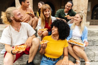 İtalya 'da pizzanın tadını çıkaran mutlu gençler. Yaz tatili sırasında çok ırklı bir grup yiyeceği paylaşıyor. Seyahat ve yaşam tarzı kavramı.