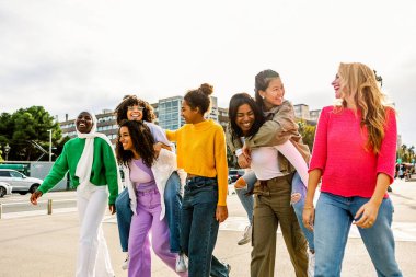 Güneşli bir sokakta genç arkadaşlar birlikte yürüyor ve gülüyorlar. Neşeli bir grup kadın dışarıda kahkahaları ve bağlantıları paylaşıyor. Arkadaşlık ve yaşam tarzı kavramı.