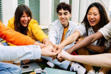 Bir grup üniversite öğrencisi destek ve işbirliği göstererek el ele tutuşuyor. Birbirlerini destekleyen ve motive eden sınıf arkadaşlarının gençlik cemiyeti. Ellere odaklan.