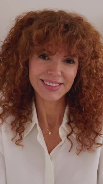 Dikey video. POV kamera görüntüsü ya da ofisteki mutlu çekici iş kadınının ön portresi. Orta yaşlı bir kadının ev ofisinden kameraya gülümseyen bir fotoğrafı..