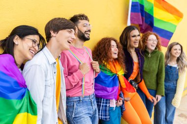 Gökkuşağı bayrağıyla ayakta duran çeşitli LGBT arkadaşları. Gençler dışarıda birlikte gülüyor ve gururu kutluyorlar. Katılım ve eşitlik kavramı.