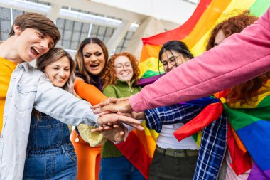 LGBT Pride 'da el ele tutuşan bir grup arkadaş. Çeşitli gençler gökkuşağı bayrağı altında birlik gösteriyor. Dayanışma ve toplum kavramı.