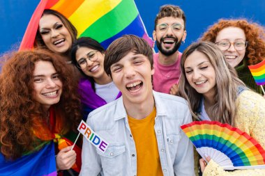 LGBT Pride 'ı kutlayan çeşitli arkadaşların portresi. Gökkuşağı yelpazesi ve bayrağıyla poz veren mutlu gençler. Çeşitlilik ve yaşam tarzı konsepti.