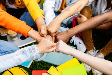 Bir grup üniversite öğrencisi destek ve işbirliği göstererek el ele tutuşuyor. Birbirlerini destekleyen ve motive eden sınıf arkadaşlarının gençlik cemiyeti