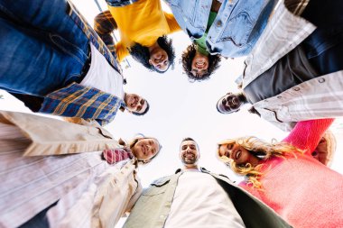 Çember halinde kameraya bakan genç insanların düşük açılı görüntüsü. Dışarıda milenyum dostlarının gülümseyen portresi..