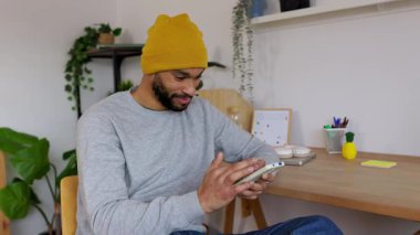 Genç, Afro-Amerikalı bir adam ev telefonuyla dinleniyor. Yaratıcı profesyonel sıradan bir anda dijital iletişimden keyif alıyor. Teknoloji ve yaşam tarzı kavramı.