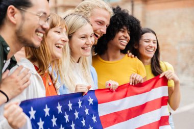 Amerika Birleşik Devletleri bayrağıyla gülümseyen genç Amerikalı arkadaşlar. Birlik, çeşitlilik ve ulusal kimliği birlikte kutlayan bir grup. Topluluk ve gurur kavramı.