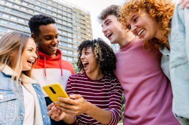 Dışarıda birlikte gülen bir grup çok ırklı öğrenci. Neşeli öğrenciler şehir ortamında sosyal zamanın tadını çıkarıyorlar. Arkadaşlık ve yaşam tarzı kavramı.