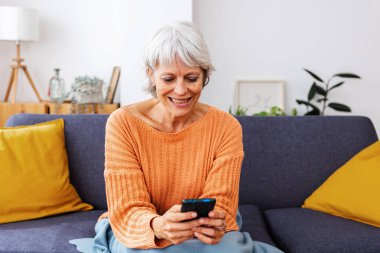 Kış gününün tadını çıkarırken cep telefonuyla eğlenen, haber okuyan ya da uygulamadan sosyal medya içeriğini izleyen son sınıf öğrencisi mutlu bir kadın. Teknoloji yaşam tarzı konsepti.