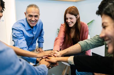 Çeşitli iş adamları iş yerinde el ele tutuşarak takım çalışmasını, birliği, stratejiyi, başarıyı ve ortaklığı sembolize ediyor. Takım çalışması ve iş konsepti