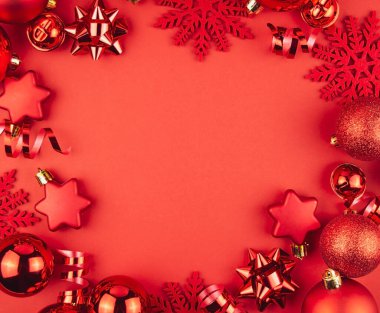 Kırmızı toplardan, yılanbalığından ve kırmızı arka planda yıldızlardan oluşan bir Noel çerçevesi. Tatil Noel süsleri. Noel arkaplanı. Pankart, kartpostal. Düz yatıyordu. Boşluğu kopyala.