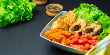 Koyu arkaplanda sebzeli fırında balık. Uzayı kopyala Yan görünüm.