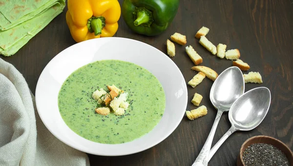 Green zucchini or broccoli cream soup on a wooden table. Green soup. Vegetarian dish. Flat lay. Copy space.