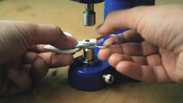 En läderarbetare använder en press för att sätta en metall niten på en äkta läderprodukt — Stockvideo