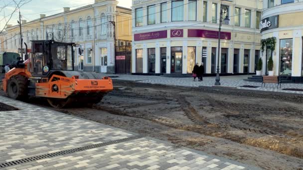 10 stycznia 2021 Taganrog, Rosja. Rolka zagęszczarki toczy się i bije ziemię. Budowa dróg. Sprzęt budowlany na remont drogi w r. Stare miasto o zachodzie słońca. — Wideo stockowe