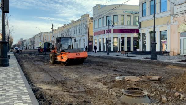 10 stycznia 2021 Taganrog, Rosja. Rolka zagęszczarki toczy się i bije ziemię. Budowa dróg. Sprzęt budowlany na remont drogi w r. Stare miasto o zachodzie słońca. — Wideo stockowe