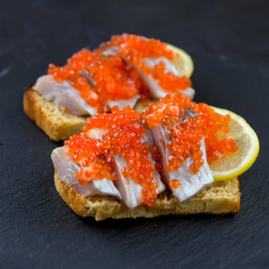 Sandviç kırmızı havyar, ringa balığı ve limon ile