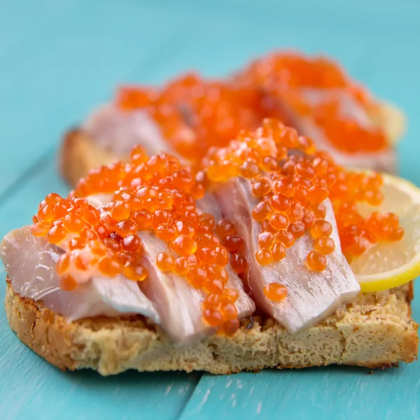 Sandwiches with red caviar, herring and lemon Royalty Free Stock Photos