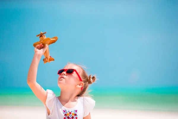 Menina feliz com brinquedo avião em mãos na praia de areia branca — Fotografia de Stock