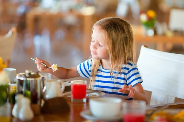 Liebenswertes kleines Mädchen frühstückt im Café im Freien — Stockfoto