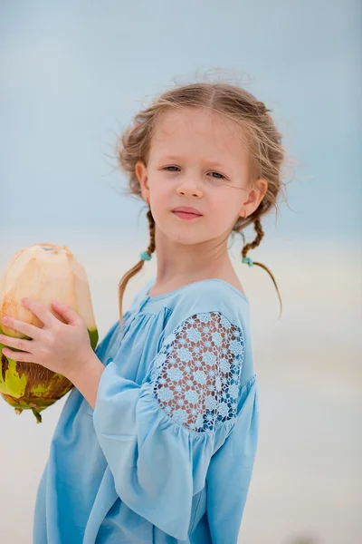 Niña adorable bebiendo leche de coco en la playa — Foto de Stock