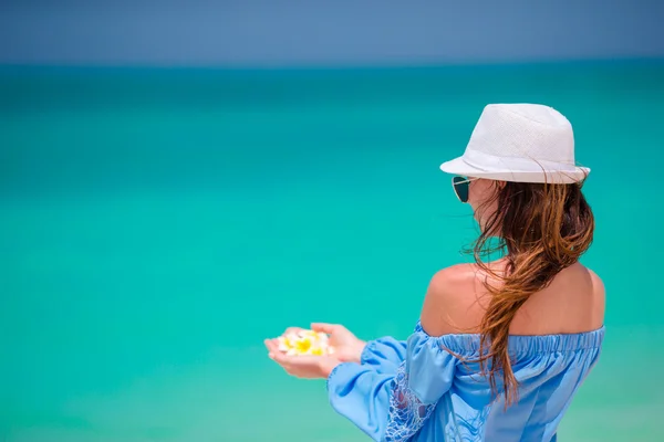 Belles fleurs frangipani dans les mains féminines fond mer turquoise sur la plage blanche — Photo