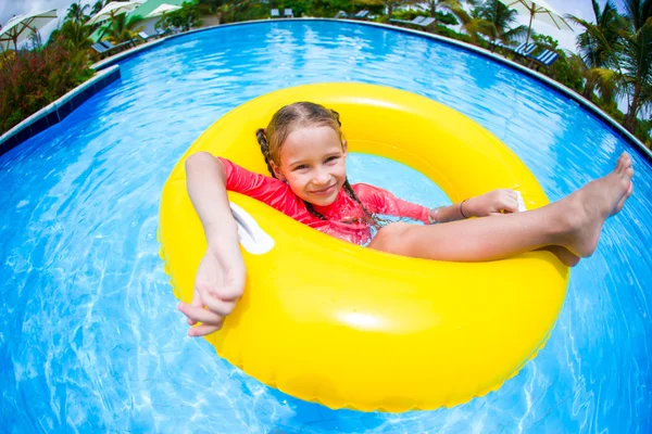 Gelukkig klein meisje met opblaasbare rubberen cirkel plezier in zwembad — Stockfoto