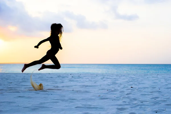 Silhueta de adorável menina na praia branca ao pôr do sol — Fotografia de Stock