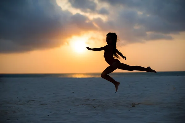 Silhueta de adorável menina na praia branca ao pôr do sol — Fotografia de Stock