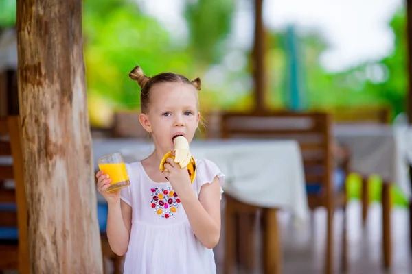 Adorable niña con jugo y plátano en la cafetería al aire libre — Foto de Stock