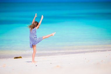 Adorable little girl having fun making cartwheel on tropical white sandy beach clipart
