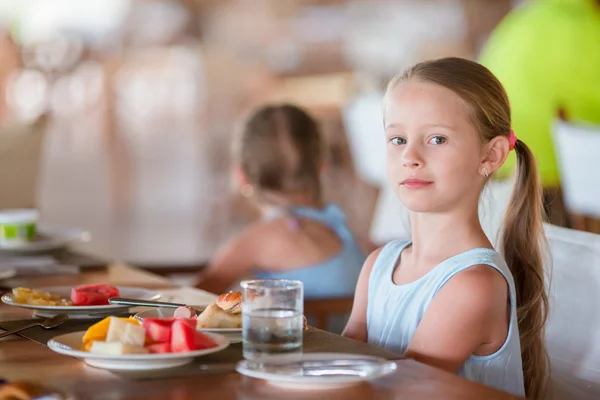 Liebenswertes kleines Mädchen frühstückt im Café im Freien — Stockfoto