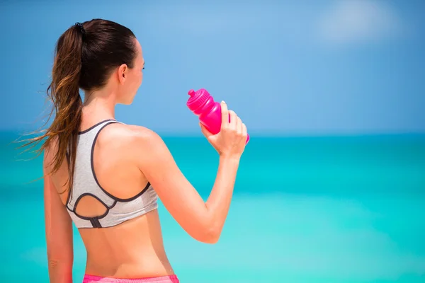 Dopasowanie aktywna kobieta młody napój wody na białej plaży — Zdjęcie stockowe