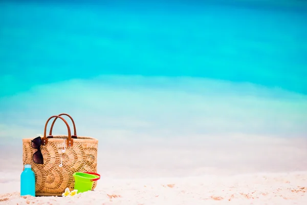 Acessórios de praia - saco de palha, garrafa de creme solar e óculos de sol vermelhos na praia — Fotografia de Stock