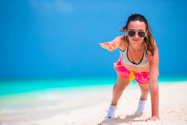 Jonge vrouw fitness doen push ups oefening op strand — Stockfoto