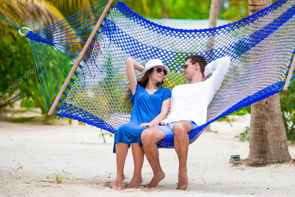 Happy couple on tropical vacation relaxing in hammock