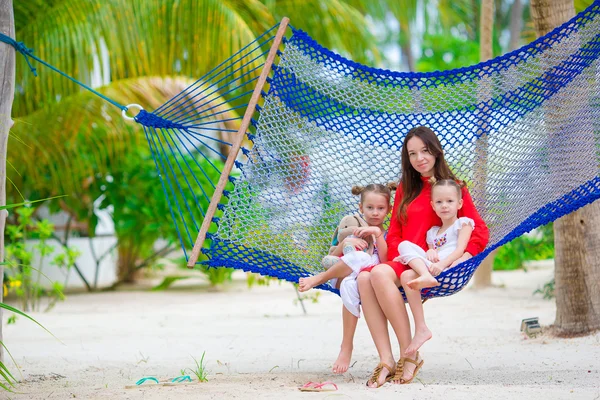 Mãe e dois filhos sentados na rede na praia tropical — Fotografia de Stock