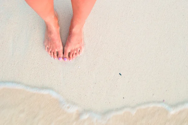 Pés de mulher na praia de areia branca em águas rasas — Fotografia de Stock