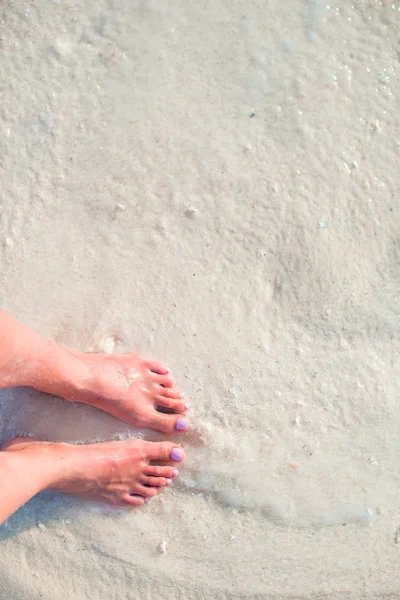 Womans feet on the white sand beach in shallow water — Stock Photo, Image