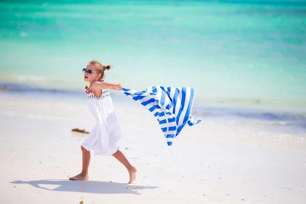 Little girl having fun running with towels on tropical beach — Stock Photo, Image