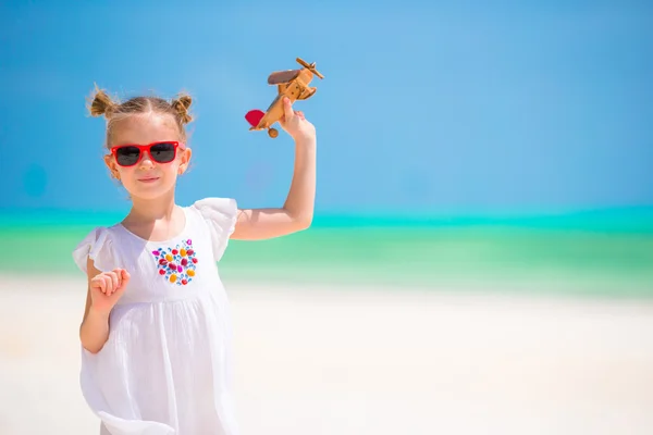 Adorable little girl with toy airplane on white beach — Stock Photo, Image