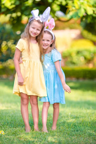 Dvě roztomilé sestřičky na sobě uši na velikonoční den venku — Stock fotografie
