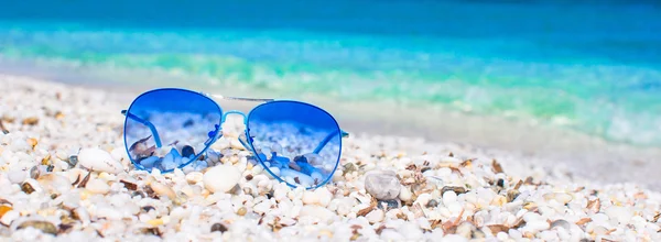 Close-up de óculos de sol azuis coloridos na praia tropical — Fotografia de Stock