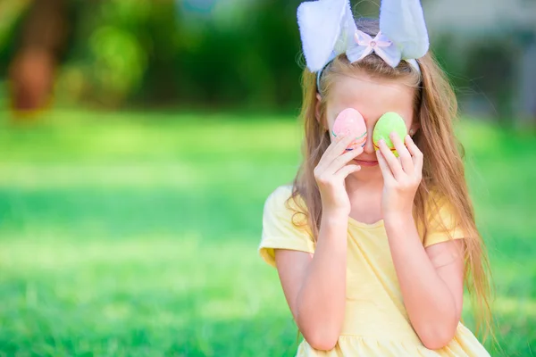 Concepto de Pascua. Adorable niña pequeña con orejas de conejo con huevos de Pascua en el día de primavera — Foto de Stock