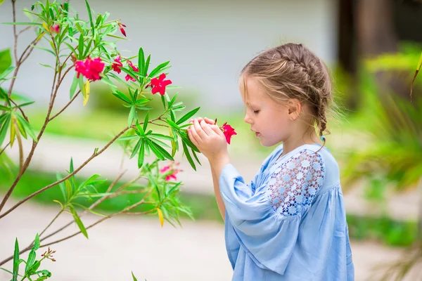 Roztomilá holčička, vonící barevných květin venku — Stock fotografie