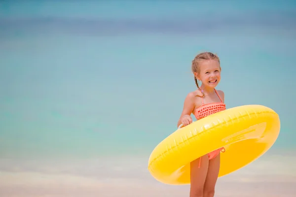 Adorable girl with inflatable rubber circle on white beach ready for swimming — Stock Photo, Image