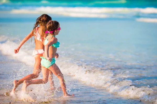 Niñas divirtiéndose en la playa tropical durante las vacaciones de verano jugando juntas en aguas poco profundas — Foto de Stock