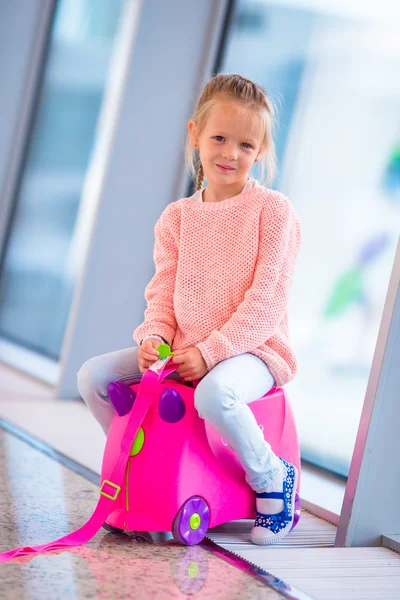 Liebenswertes kleines Mädchen im Flughafen mit ihrem Gepäck, das auf das Boarding wartet — Stockfoto