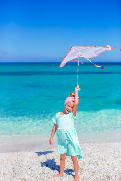 Szczęśliwa dziewczynka gra z latający latawiec na tropikalnej plaży — Zdjęcie stockowe