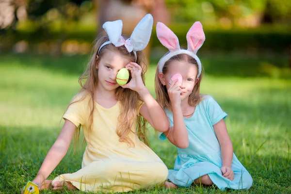 Two adorable little sisters wearing bunny ears on Easter day outdoors — Stock Photo, Image